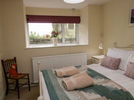 A bedroom with a bed with folded towels and pillows a chair with a stuffed toy and a window with flowers on the sill at Fox Barn in Staveley