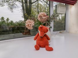 A stuffed fox toy and a vase with flowers on a white windowsill at Fox Barn in Staveley