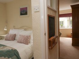 A bedroom with a bed with pillows and a lamp next to a hallway with a blackboard and a view into another room with a window and wardrobe at Fox Barn in Staveley