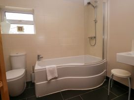 A bathroom with a bathtub shower combination toilet sink stool and a small window at Fox Barn in Staveley