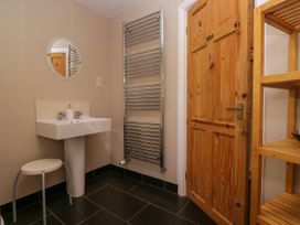 A bathroom with a sink a round mirror a wooden door a metal towel radiator and a wooden shelving unit at Fox Barn in Staveley