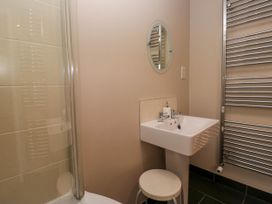 A bathroom with a sink a round mirror a stool a shower enclosure and a heated towel rail at Fox Barn in Staveley