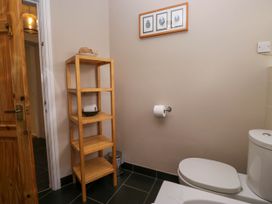 A bathroom with a wooden shelf unit a toilet and a framed picture on the wall at Fox Barn in Staveley