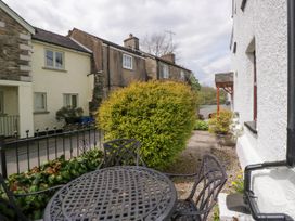 An outdoor seating area with metal table and chairs next to a white building and a yellow bush at Fox Barn in Staveley