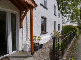 Exterior view of a white textured house with wooden porch over entrance and small garden with plants behind a metal fence at Fox Barn in Staveley