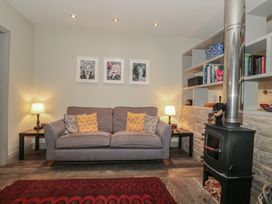 A living room with a sofa, lamp, and stove at The Stable in Deepdean near Ross-on-Wye