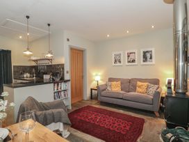 A living room with a sofa and kitchen area at The Stable in Deepdean near Ross-on-Wye