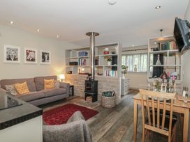 A living room with a sofa, wooden stove, and dining area at The Stable in Deepdean near Ross-on-Wye