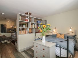 A bedroom featuring a bed with a shelf and a vase of flowers at The Stable Deepdean near Ross-on-Wye