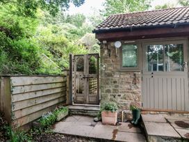 An outdoor area with a wooden gate and stone wall at The Stable in Deepdean near Ross-on-Wye