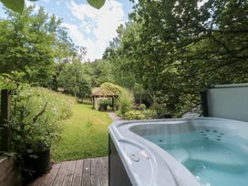A hot tub overlooking a garden pathway and shelter at The Stable in Deepdean near Ross-on-Wye