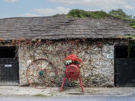 An outdoor view of a stone building with a cart and wagon wheel at Ryan's Loft in Ardfinnan near Clonmel, County Tipperary