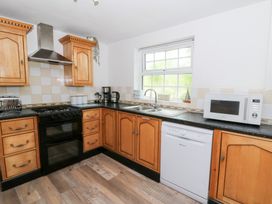 A kitchen with wooden cabinets and appliances at Cariad Cottage in Cross Inn