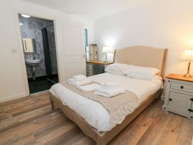 A bedroom with a bed and bathroom access at Cariad Cottage Cross Inn