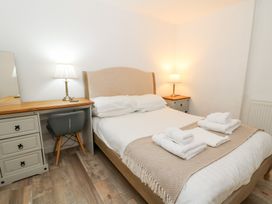 A bedroom with a bed, desk, and lamps at Cariad Cottage in Cross Inn