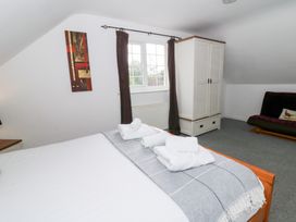 A bedroom with a bed and wardrobe at Cariad Cottage Cross Inn