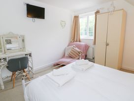 A bedroom with a bed, dresser, and television at Cariad Cottage in Cross Inn