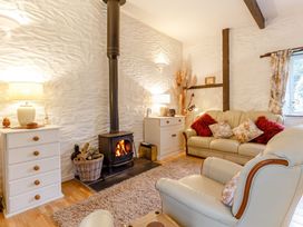 A living room with a wood stove and seating at Wagtail Cottage in East Taphouse
