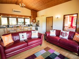 A living room with a sofa and kitchen area at Sycamore Lodge Nantmel near Rhayader