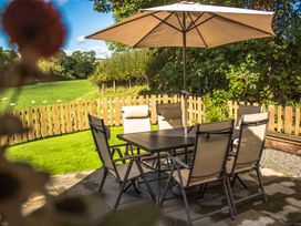 An outdoor dining area with a table and chairs under an umbrella at Sycamore Lodge Nantmel near Rhayader