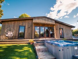 An outdoor area with a hot tub and a wooden building at Sycamore Lodge in Nantmel near Rhayader