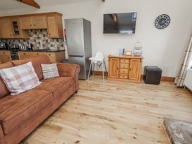A living room with a sofa, television, and high chair at Grey Croft in Embleton