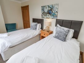 A bedroom with twin beds and a nightstand with a lamp at Grey Croft in Embleton