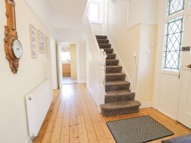 A hallway with a staircase and wall clock at Meadway House in Rhos-on-Sea