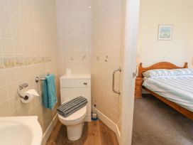 A bathroom with a toilet and sink, with a bedroom visible in the background at Meadway House in Rhos-on-Sea