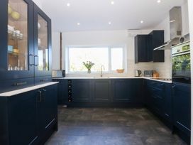 A kitchen with dark cabinets and a window at Monarfon Benllech near Red Wharf Bay