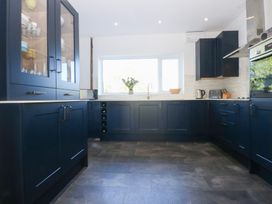 A kitchen with dark cabinets and a window at Monarfon in Benllech near Red Wharf Bay