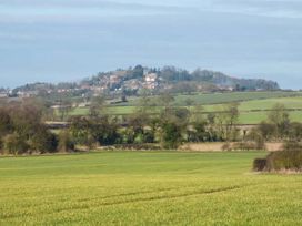 A green field with trees and a village on a hill in the distance at The Stables Crayke Lodge in Easingwold