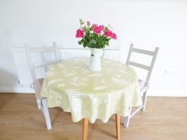 A round table with a floral tablecloth and a vase with pink flowers with two chairs at The Stables Crayke Lodge in Easingwold