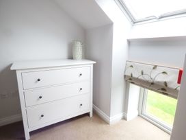 A white chest of drawers with a vase on top next to a window with a floral Roman blind at The Stables Crayke Lodge in Easingwold