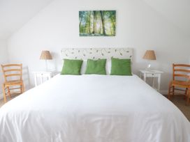 A bedroom with a large bed with green pillows two bedside tables with lamps and wooden chairs at The Stables Crayke Lodge in Easingwold