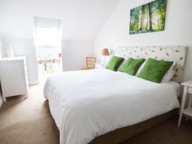 A bedroom with a white bed and green pillows a dresser a wooden chair and a lamp at The Stables Crayke Lodge in Easingwold