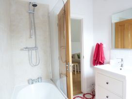 A bathroom with a bathtub shower combination and towels hanging near a sink at The Stables Crayke Lodge in Easingwold
