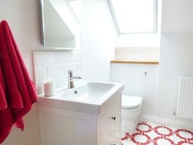 A bathroom with a sink cabinet mirror toilet red towels and patterned red and white floor tiles at The Stables Crayke Lodge Easingwold