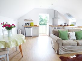 A kitchen and living room area with a table set with flowers a sofa and kitchen appliances at The Stables Crayke Lodge in Easingwold