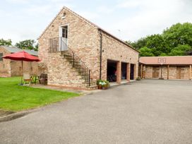 A brick garage with an outdoor staircase and a seating area with a red umbrella at The Stables Crayke Lodge in Easingwold