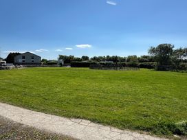 An open grassy field with a paved path and a building in the background at The Mill in Abererch near Pwllheli