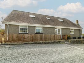 A house with a gravel driveway and a wooden fence at Ty Ni Caeathro near Caernarfon