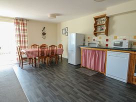 A kitchen with dining table and appliances at Ty Ni in Caeathro near Caernarfon