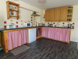 A kitchen with appliances and wooden cabinets at Ty Ni Caeathro near Caernarfon