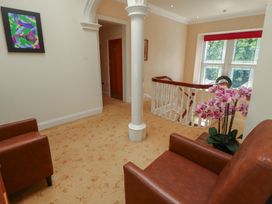 A hallway with chairs and a plant at Eden Lodge in Bardsea