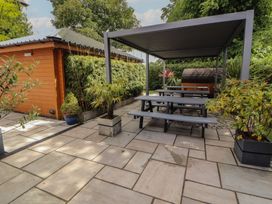 A garden with a table and benches under a canopy at Eden Lodge in Bardsea