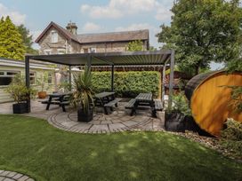 An outdoor seating area with a pergola and dining table at Eden Lodge in Bardsea