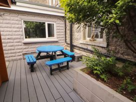 An outdoor seating area with a round blue table and benches at Eden Lodge in Bardsea
