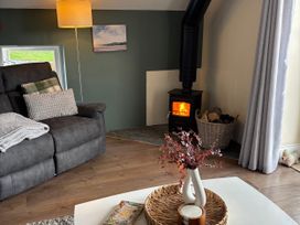 A living room with a stove and a sofa at Ysgubor - The Barn Boncath near Crymych