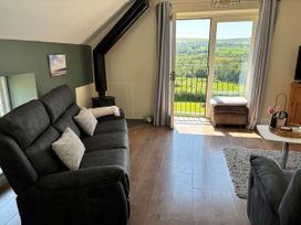 A living room with a sofa and door leading to a view at Ysgubor - The Barn Boncath near Crymych